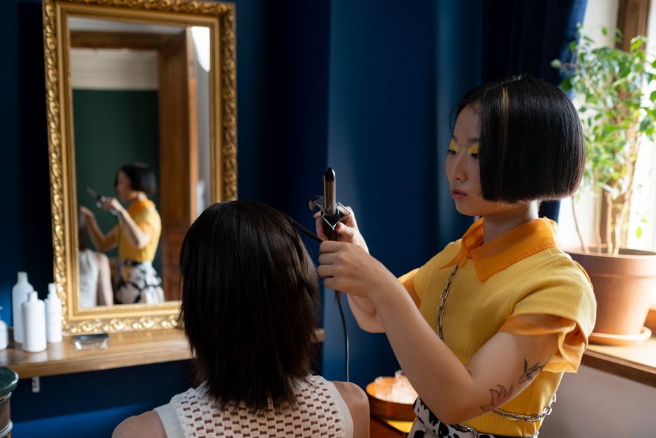 Hairdresser styling client's hair in a chic salon with a focus on detailed hair work.