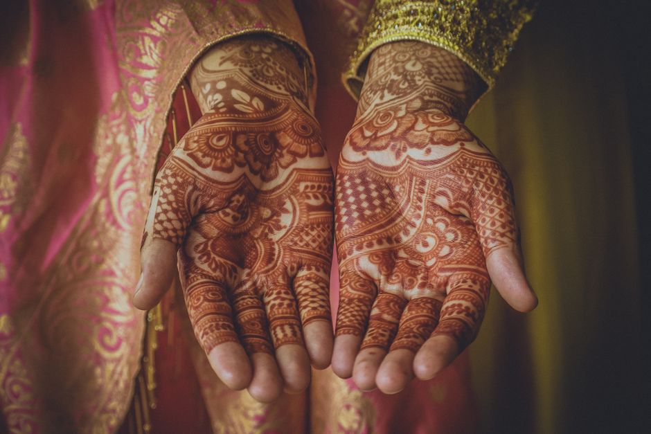 Intricate henna designs on a woman's hands in close-up, showcasing traditional artistry.