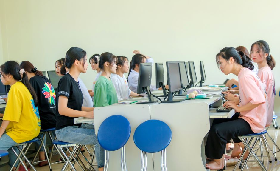 Students in a computer lab working together on computers, showcasing teamwork and education.