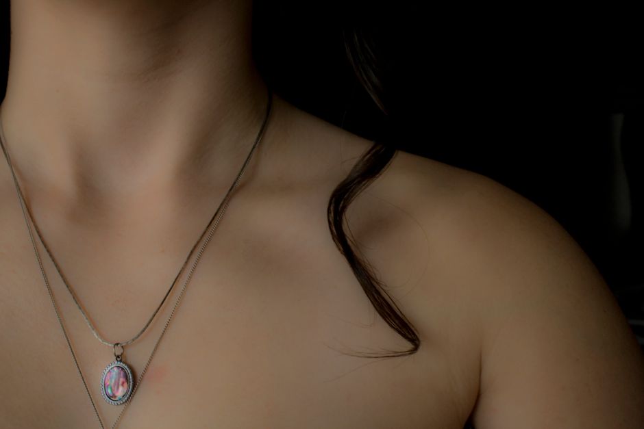 Close-up of a woman's collarbone wearing a delicate necklace, highlighting elegant jewelry.