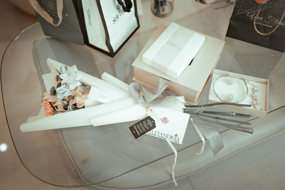 Stylish display of gift boxes, flowers, and jewelry on a glass table.