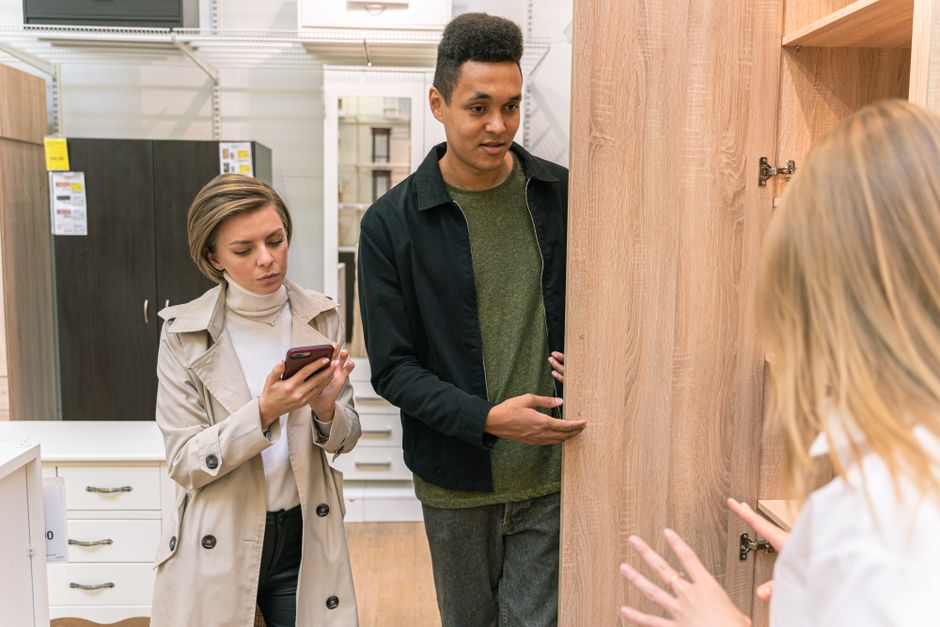 A man and woman shopping for wooden furniture in a modern retail store setting.