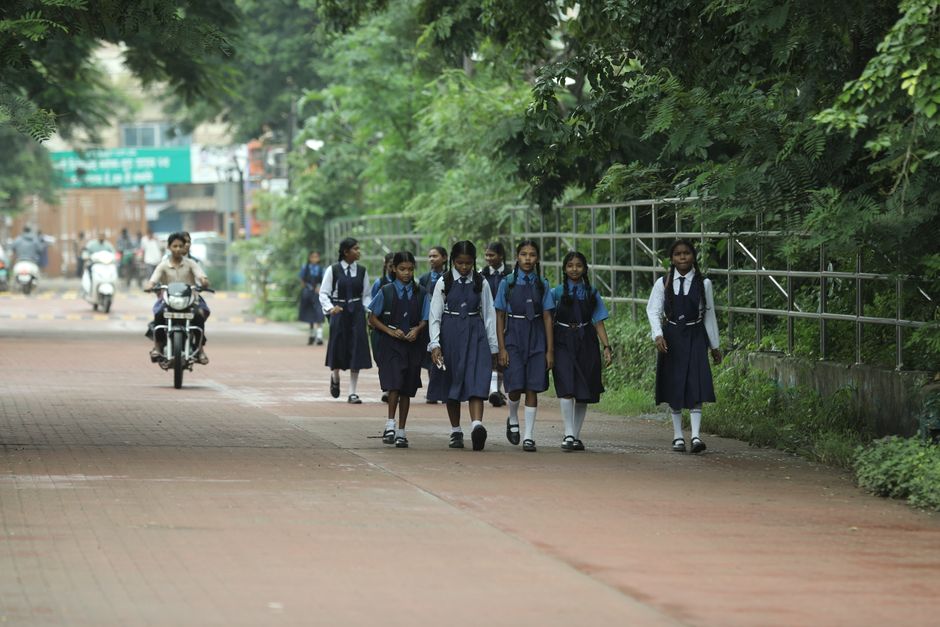 Group of schoolgirls walking along a tree-lined street in Raipur, India.