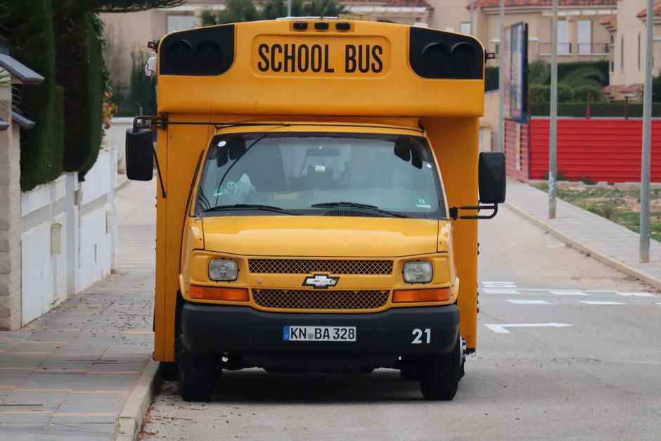 Front view of a yellow school bus parked along a quiet urban street. Street view