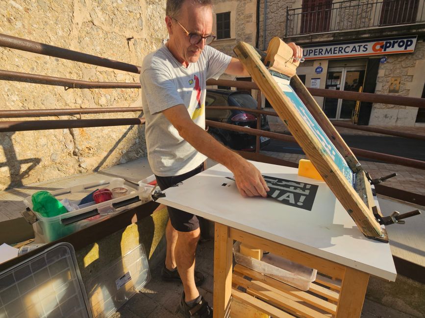Man engaged in screen printing setup outdoors in Mallorca village.