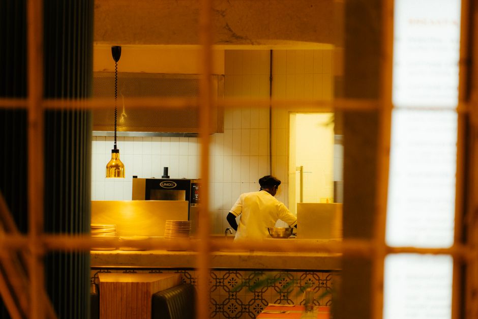 A professional chef preparing food in a warm, inviting restaurant kitchen at night.