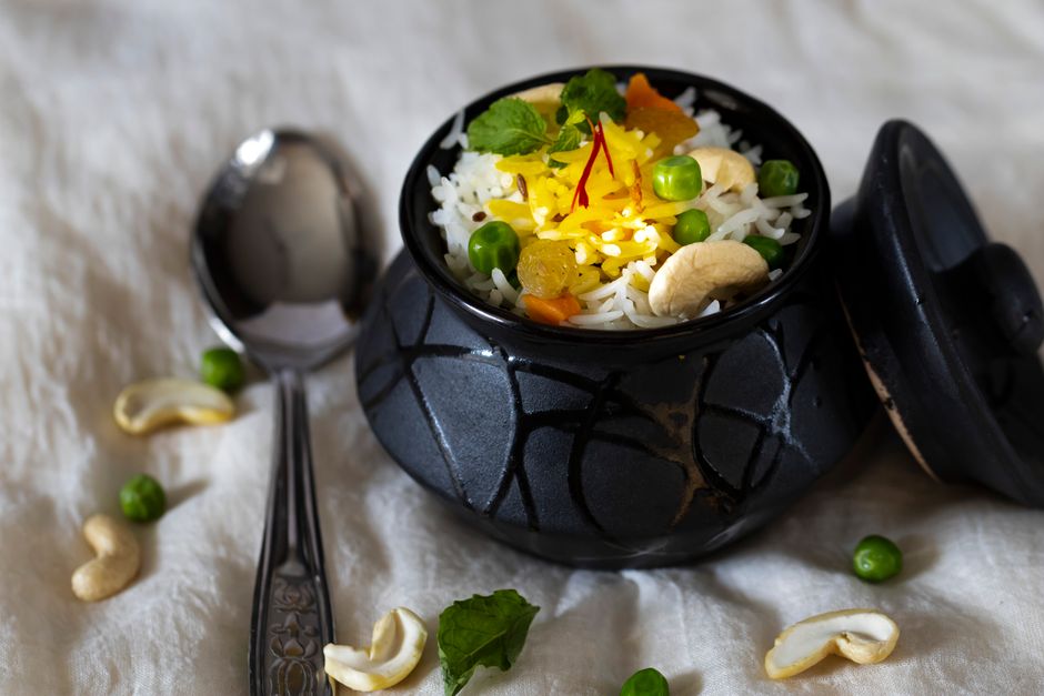 Authentic Indian rice with peas, cashews, and saffron in a black pot. Perfect for culinary themes.