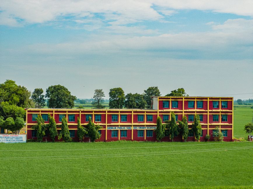 Colorful school building amidst lush green fields in Ludhiana, Punjab, India.