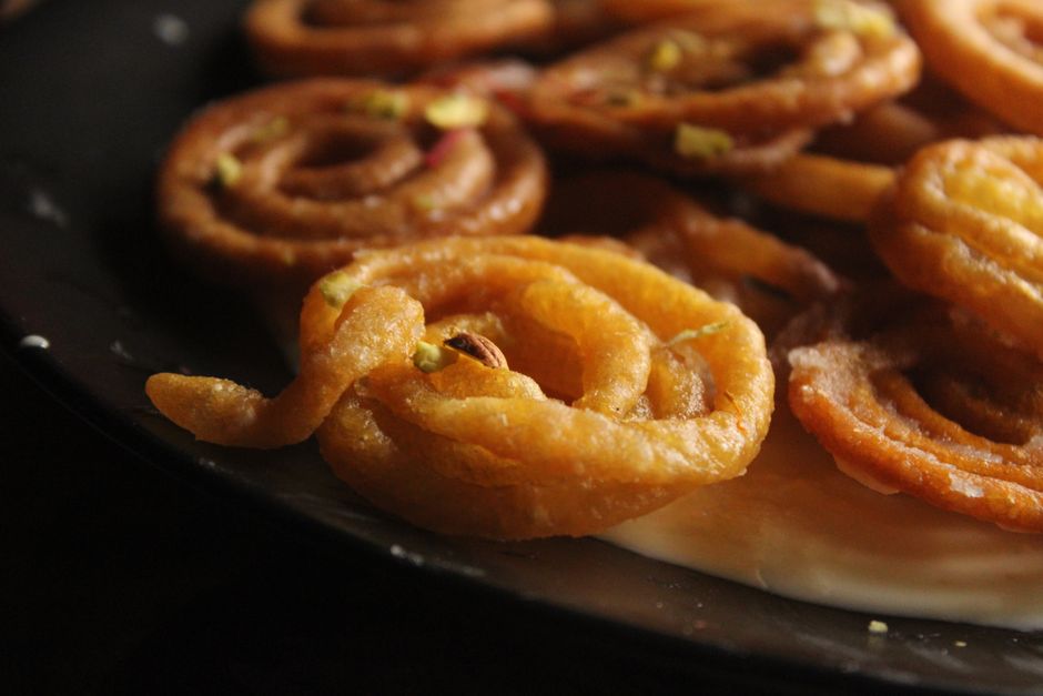 Delicious close-up view of golden jalebi sweets with pistachios, a popular Indian treat.