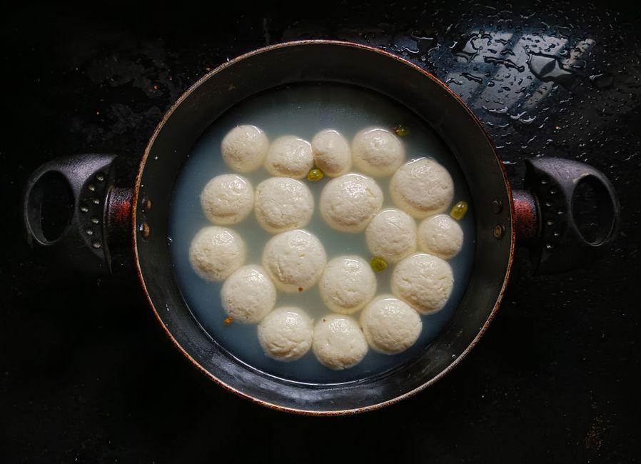 Overhead view of traditional Indian rasgulla sweets cooking in syrup.